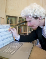 Noah Brenner playfully attempts to write music on a computer using a quill.